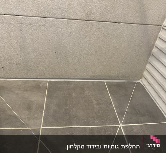 רצפת אריחים בפינת חדר עם קיר אפור